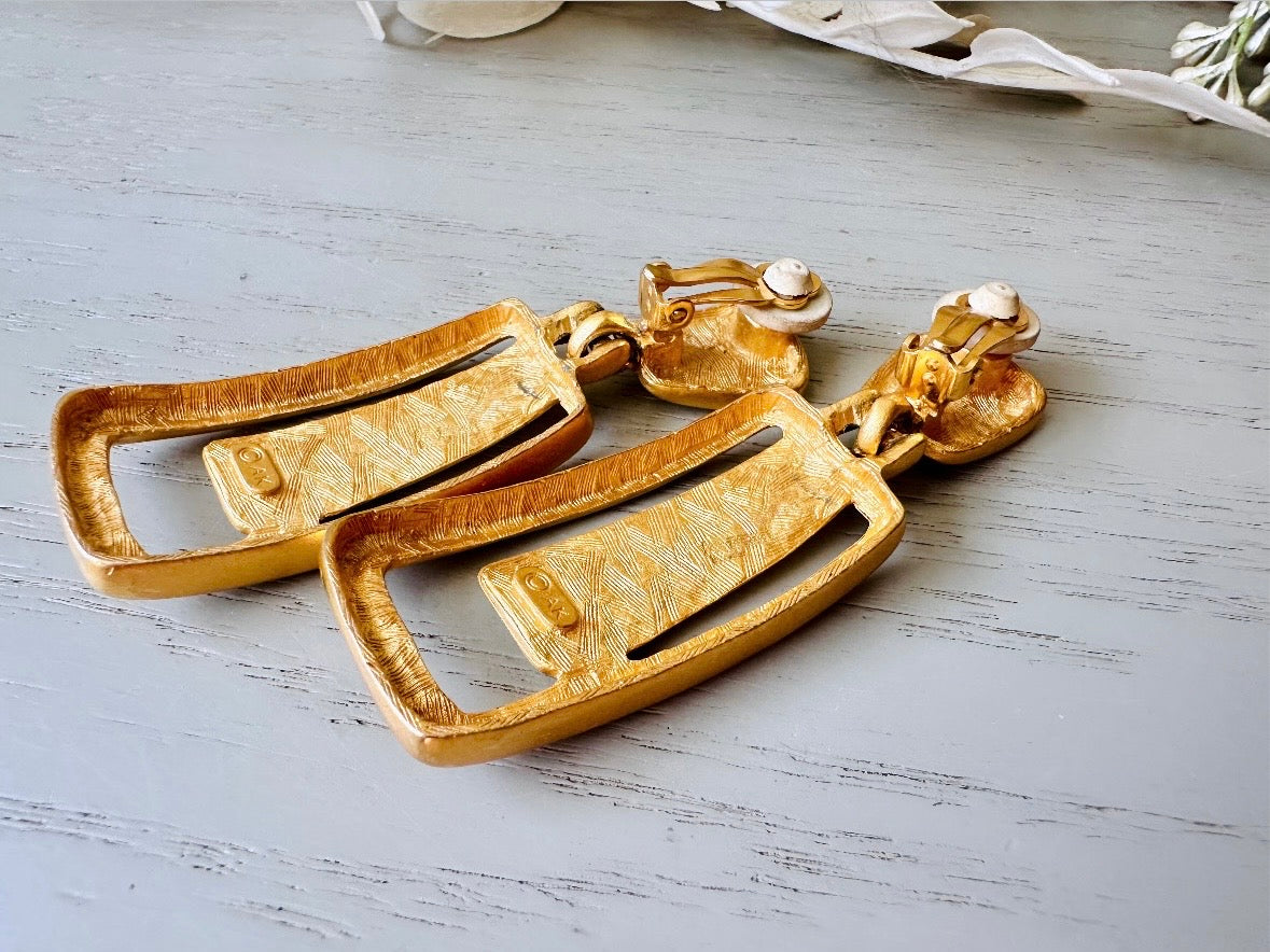 These Anne Klein vintage matte gold designer earrings are spectacular. Full of 1980s bold glamour, these clip ons have a satin gold finish and a geometric design. These vintage dangle earrings are bold and elegant, with curved square posts and rectangular drops with a cut out hollow border. These are big and incredibly well made in a satin matte gold finish. Clip on style, easy to wear and in great vintage condition. Highly sought after designer vintage. 