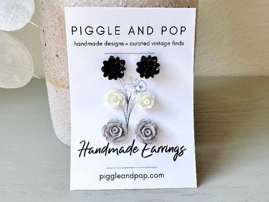 This lovely flower stud earring set of monochromatic flowers is a classic staple for any jewelry box! This floral post earring set features one pair of black lotus earrings, one pair of white rose studs and one pair of matte grey open rose earrings. They are made with glossy resin and hypoallergenic surgical steel posts.