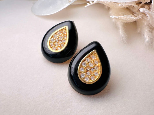 Black teardrop-shaped earrings with gold and crystal details on a light background
