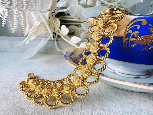 This bold 1970s vintage gold chain bracelet is so unique- featuring a textured gold tone finish with interconnected circular links resembling a stylized flower shape. Twisted rope detail on the outer loops adds even more interest. Structural matte gold jewelry is both timeless and currently trending. A one of a kind bracelet and perfect jewelry gift for the vintage lover. In excellent vintage condition from Piggle and Pop