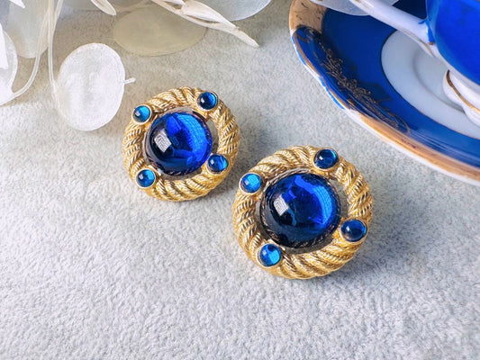 These vintage Park Lane gold rope earrings with cobalt blue cabochons are absolutely out of this world! Vibrant deep blue cabochons glow as they are surrounded by an intricate gold rope border that is accented with four more smaller blue jewels. These stones are so vibrant and vividly pop against their gold setting. Ultimate 80s mega star vibes, post style for pierced ears. Highly collectible signed designer pair in excellent vintage condition, no major flaws to note.