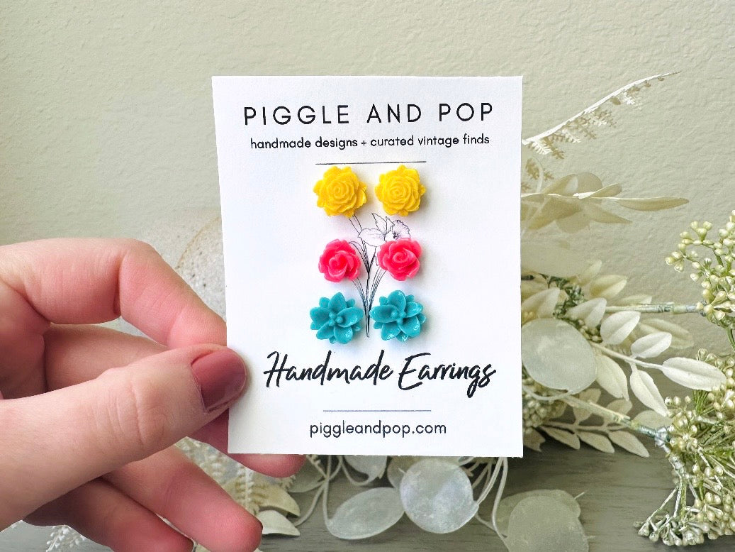 Colorful Flower Earring Set, Yellow Pink Teal Rose Post Earrings from Piggle and Pop held in hand
