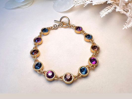 Gold Monet bracelet with multicolored gemstones on a light background