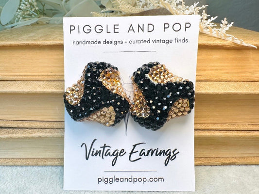 These glamorous vintage Richard Kerr cocktail earrings are spectacular. Sparkling black and gold pave set Swarovski crystals cover the entirety of the earrings, these statement earrings are the height of 80s glam. Featuring a sculptural 3d shape like a knot. The gold component is a rich topaz hue.  
Clip on style, in great vintage condition.
