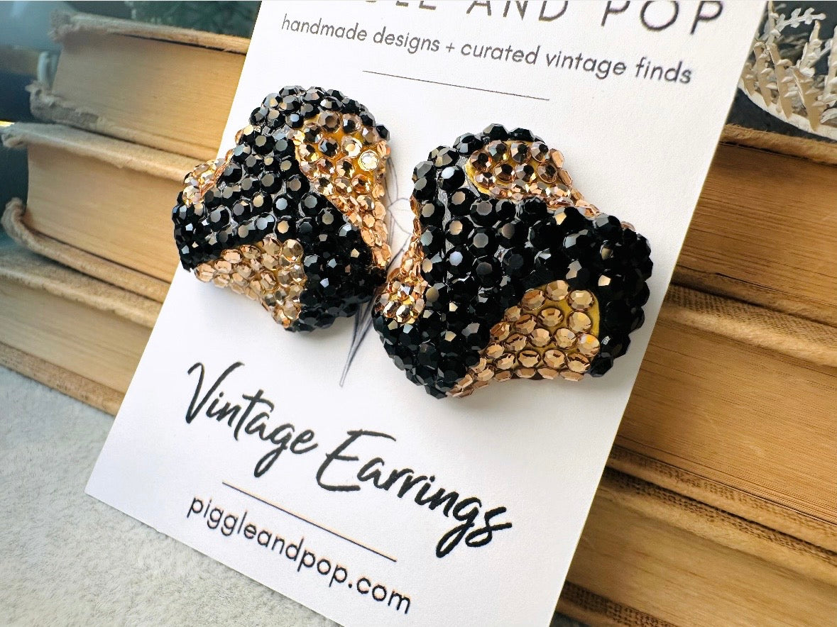 These glamorous vintage Richard Kerr cocktail earrings are spectacular. Sparkling black and gold pave set Swarovski crystals cover the entirety of the earrings, these statement earrings are the height of 80s glam. Featuring a sculptural 3d shape like a knot. The gold component is a rich topaz hue.  
Clip on style, in great vintage condition.