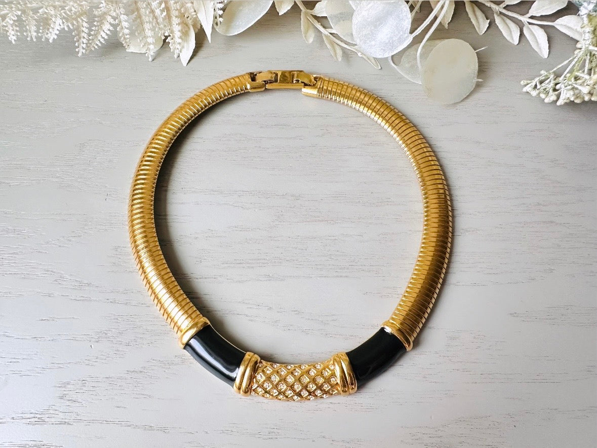 This vintage omega necklace is a stunning black and gold Monet designer vintage necklace. Featuring wide band snake chain and geometric segments of black enamel. This 1980s vintage rhinestone collar necklace has a fold over clasp and extender link. &nbsp;Excellent condition. This vintage designer necklace is high quality, weighty and well made. 