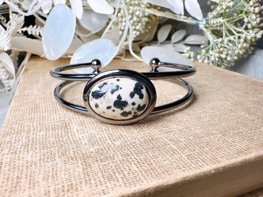 This handmade gemstone cuff bracelet features a gorgeous natural cabochon of dalmatian jasper. This jasper stone is an earthy cream-colored stone with tan and black spots. Ancient mystics and Shamans often wore jasper to provide protection. No two are exactly alike and they are just beautiful to behold. Your bracelet will have a stone very similar to the one pictured.