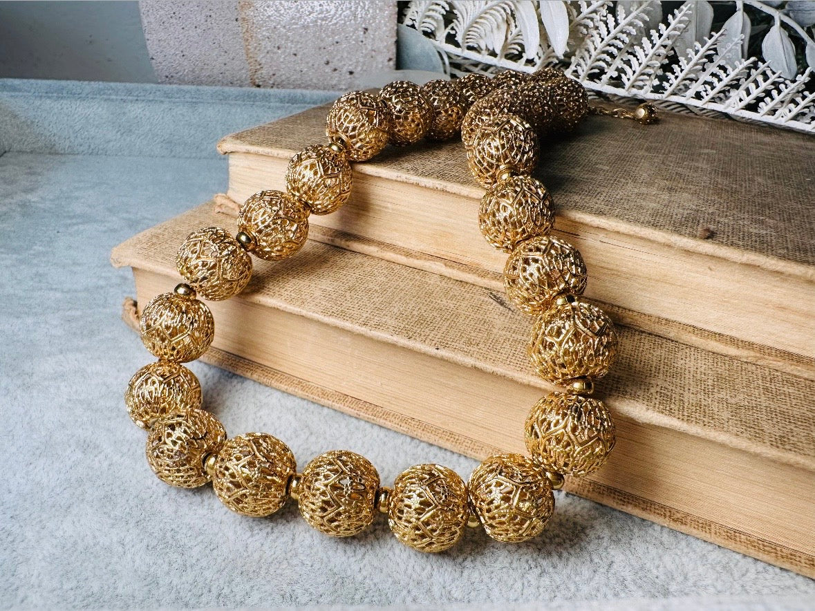 This chunky gold filigree vintage necklace is a timeless piece. Signed Monet- jewelry that is renowned for standing the test of time in both quality and style. This gold lace filigree necklace is composed of delicate and striking filigree beads with tiny gold spacers. Hook closure with beautiful gold extension chain and signature Monet hang tag. Excellent &nbsp;vintage condition- please see all pics.&nbsp;