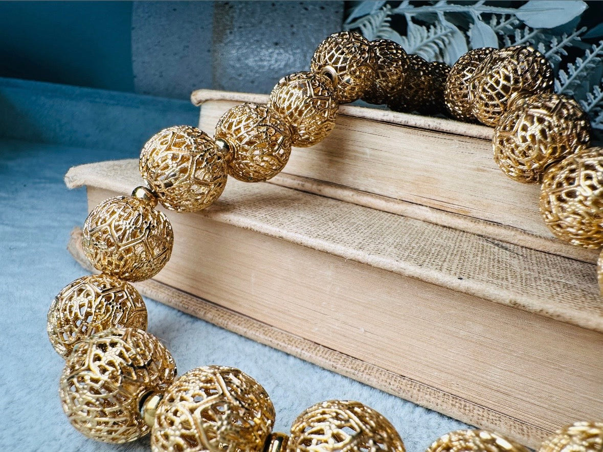 This chunky gold filigree vintage necklace is a timeless piece. Signed Monet- jewelry that is renowned for standing the test of time in both quality and style. This gold lace filigree necklace is composed of delicate and striking filigree beads with tiny gold spacers. Hook closure with beautiful gold extension chain and signature Monet hang tag. Excellent &nbsp;vintage condition- please see all pics.&nbsp;