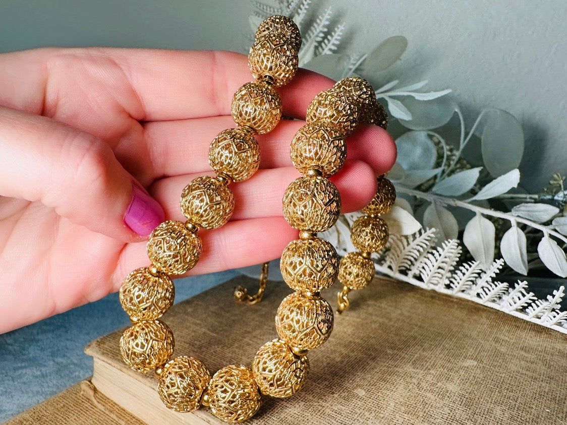This chunky gold filigree vintage necklace is a timeless piece. Signed Monet- jewelry that is renowned for standing the test of time in both quality and style. This gold lace filigree necklace is composed of delicate and striking filigree beads with tiny gold spacers. Hook closure with beautiful gold extension chain and signature Monet hang tag. Excellent &nbsp;vintage condition- please see all pics.&nbsp;