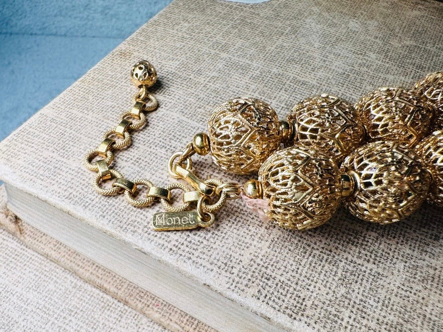 This chunky gold filigree vintage necklace is a timeless piece. Signed Monet- jewelry that is renowned for standing the test of time in both quality and style. This gold lace filigree necklace is composed of delicate and striking filigree beads with tiny gold spacers. Hook closure with beautiful gold extension chain and signature Monet hang tag. Excellent &nbsp;vintage condition- please see all pics.&nbsp;