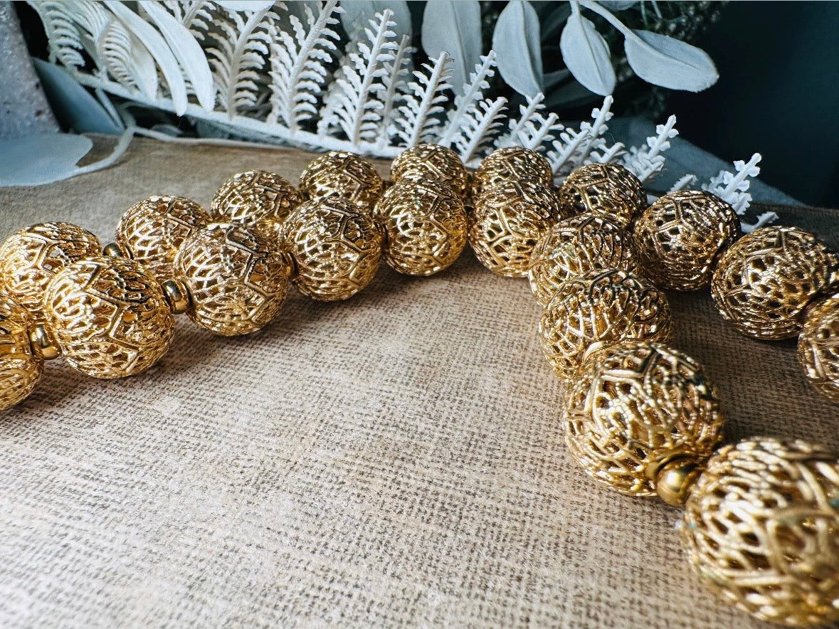 This chunky gold filigree vintage necklace is a timeless piece. Signed Monet- jewelry that is renowned for standing the test of time in both quality and style. This gold lace filigree necklace is composed of delicate and striking filigree beads with tiny gold spacers. Hook closure with beautiful gold extension chain and signature Monet hang tag. Excellent &nbsp;vintage condition- please see all pics.&nbsp;