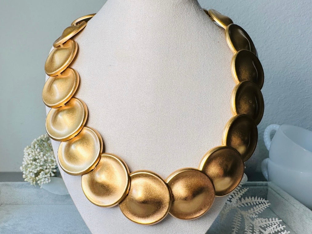 This vintage brushed gold Monet disc necklace is perfection. This vintage Cleopatra style choker is the height of 80s glamour, featuring stunning articulated satin gold discs. This necklace is so flattering on, laying perfectly on the collarbones. Adjustable hook closure with gold chain extender. Monet is renowned and well loved for beautiful jewelry that has stood the test of time. 