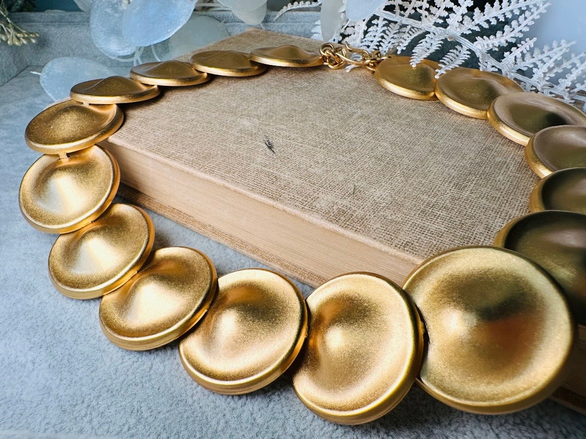 This vintage brushed gold Monet disc necklace is perfection. This vintage Cleopatra style choker is the height of 80s glamour, featuring stunning articulated satin gold discs. This necklace is so flattering on, laying perfectly on the collarbones. Adjustable hook closure with gold chain extender. Monet is renowned and well loved for beautiful jewelry that has stood the test of time. 