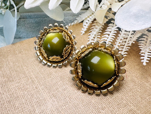 These gorgeous 1950s moonglow Caroline Emmons vintage earrings are stunning. Featuring glowing avocado green lucite cabochons set in a lacey gold open work bezel. These authentic 50s vintage earrings are gold tone base clip on style, signed on back. Their large size, incredible details and spectacular moon glow effect make them a unique collector's pair. Great vintage condition, no major flaws to note - please see pics. Such a stunning statement pair! Beautiful cocktail pair for the holidays.