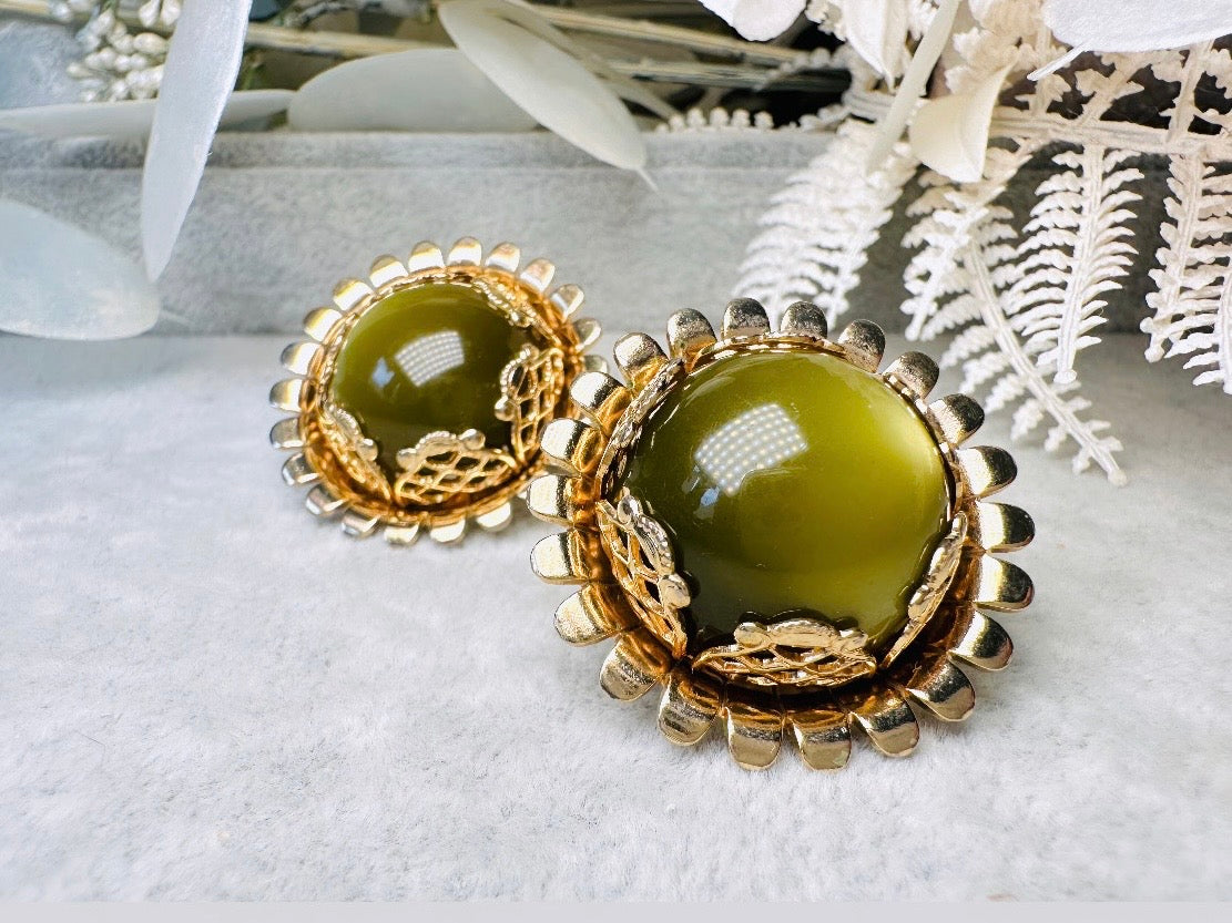 These gorgeous 1950s moonglow Caroline Emmons vintage earrings are stunning. Featuring glowing avocado green lucite cabochons set in a lacey gold open work bezel. These authentic 50s vintage earrings are gold tone base clip on style, signed on back. Their large size, incredible details and spectacular moon glow effect make them a unique collector's pair. Great vintage condition, no major flaws to note - please see pics. Such a stunning statement pair! Beautiful cocktail pair for the holidays.