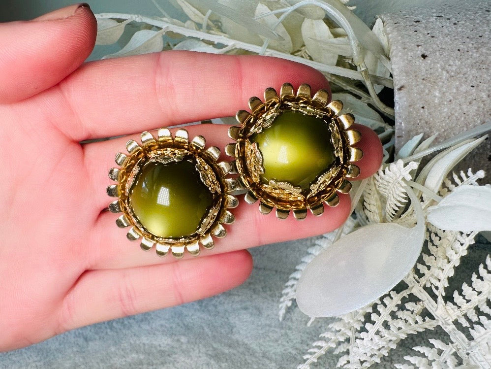 These gorgeous 1950s moonglow Caroline Emmons vintage earrings are stunning. Featuring glowing avocado green lucite cabochons set in a lacey gold open work bezel. These authentic 50s vintage earrings are gold tone base clip on style, signed on back. Their large size, incredible details and spectacular moon glow effect make them a unique collector's pair. Great vintage condition, no major flaws to note - please see pics. Such a stunning statement pair! Beautiful cocktail pair for the holidays.
