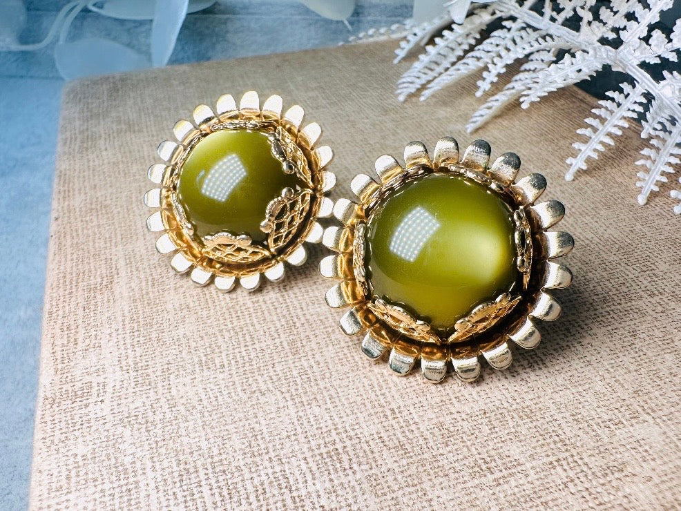 These gorgeous 1950s moonglow Caroline Emmons vintage earrings are stunning. Featuring glowing avocado green lucite cabochons set in a lacey gold open work bezel. These authentic 50s vintage earrings are gold tone base clip on style, signed on back. Their large size, incredible details and spectacular moon glow effect make them a unique collector's pair. Great vintage condition, no major flaws to note - please see pics. Such a stunning statement pair! Beautiful cocktail pair for the holidays.