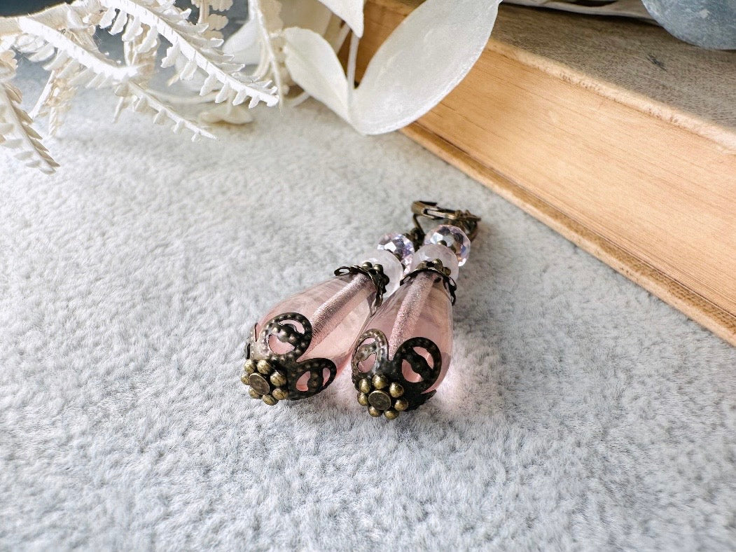 These beautiful Victorian earrings are handmade with rose quartz stones, lustrous pink Czech glass teardrop beads, and faceted crystals. These whimsical blushing rose earrings feature a delightful mix of soft pink hues and rustic bronze detailing. A wonderful pair of earrings for elegant everyday wear.
