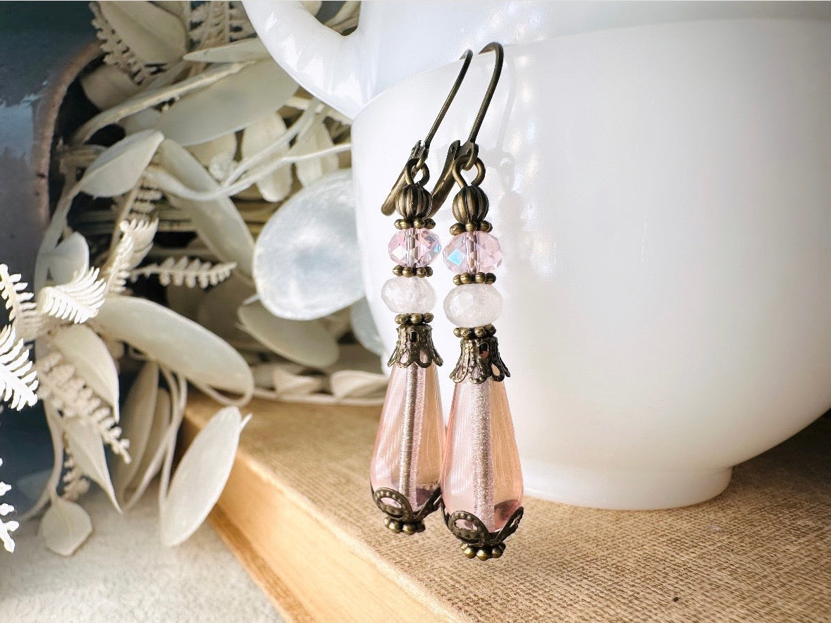 These beautiful Victorian earrings are handmade with rose quartz stones, lustrous pink Czech glass teardrop beads, and faceted crystals. These whimsical blushing rose earrings feature a delightful mix of soft pink hues and rustic bronze detailing. A wonderful pair of earrings for elegant everyday wear.