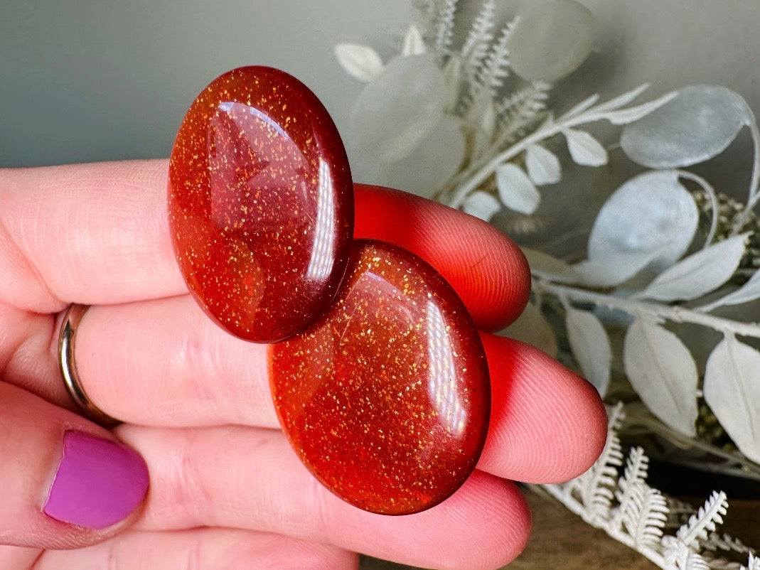 These vintage lucite button earrings from Piggle and Pop are such a gorgeous color- vibrant copper with flecks of fine gold glitter. These retro clip ons are from the 1960s. A fun party pair, these confetti earrings were wildly popular at the time and a fun statement pair to rock in modern day. Lightweight for their size, a round slightly domed coin shape and easy to wear in clip on style. They catch the light beautifully and can appear a deep reddish copper shade to a glowing sunset hue. 