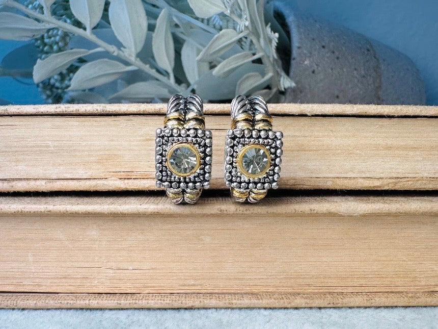 Pair of silver and gold earrings on a stack of books with a natural background