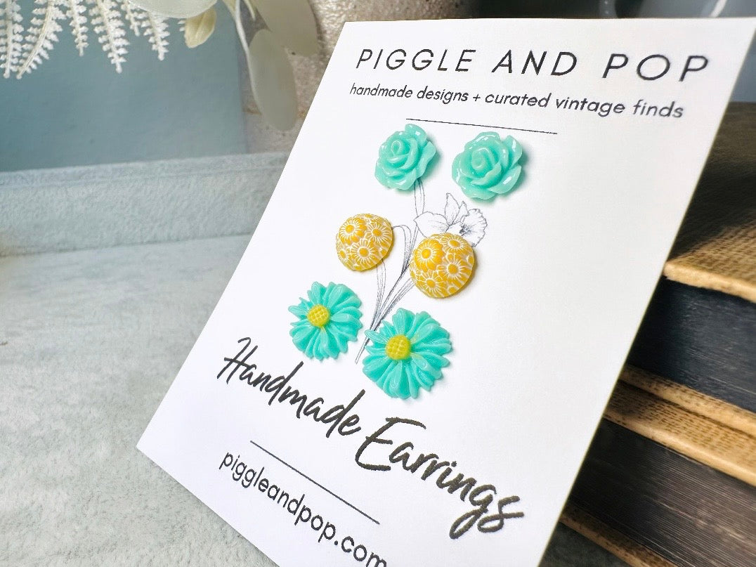 Card with handmade earrings featuring flowers on a wooden surface