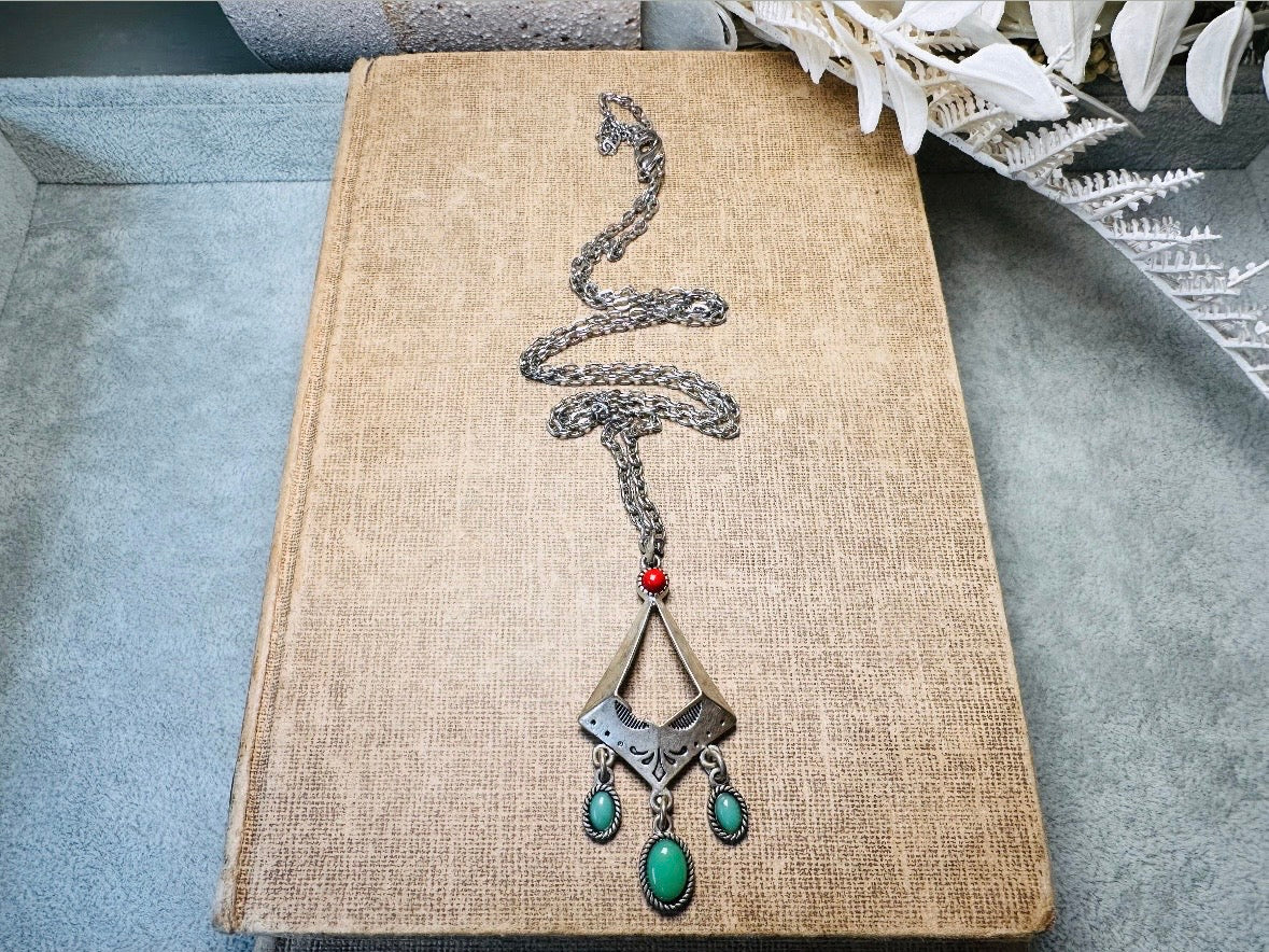 This vintage silver pendant charm necklace is full of bohemian details. Long silver curb chain with a sculptural pendant that has geometric engravings and three turquoise cabochon drops dangling from the focal. There is a red stone set at the top of the pendant. This southwestern style silver vintage necklace would look amazing featured in a necklace stack and beautiful alone.