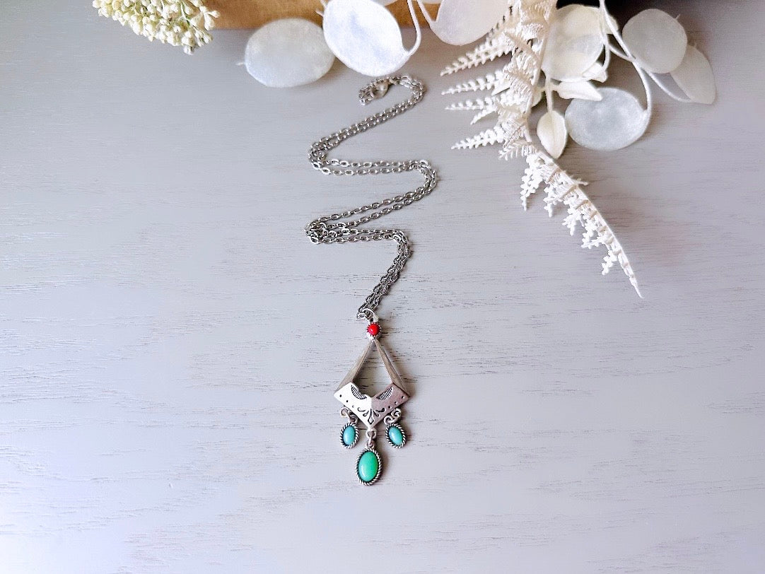 This vintage silver pendant charm necklace is full of bohemian details. Long silver curb chain with a sculptural pendant that has geometric engravings and three turquoise cabochon drops dangling from the focal. There is a red stone set at the top of the pendant. This southwestern style silver vintage necklace would look amazing featured in a necklace stack and beautiful alone.