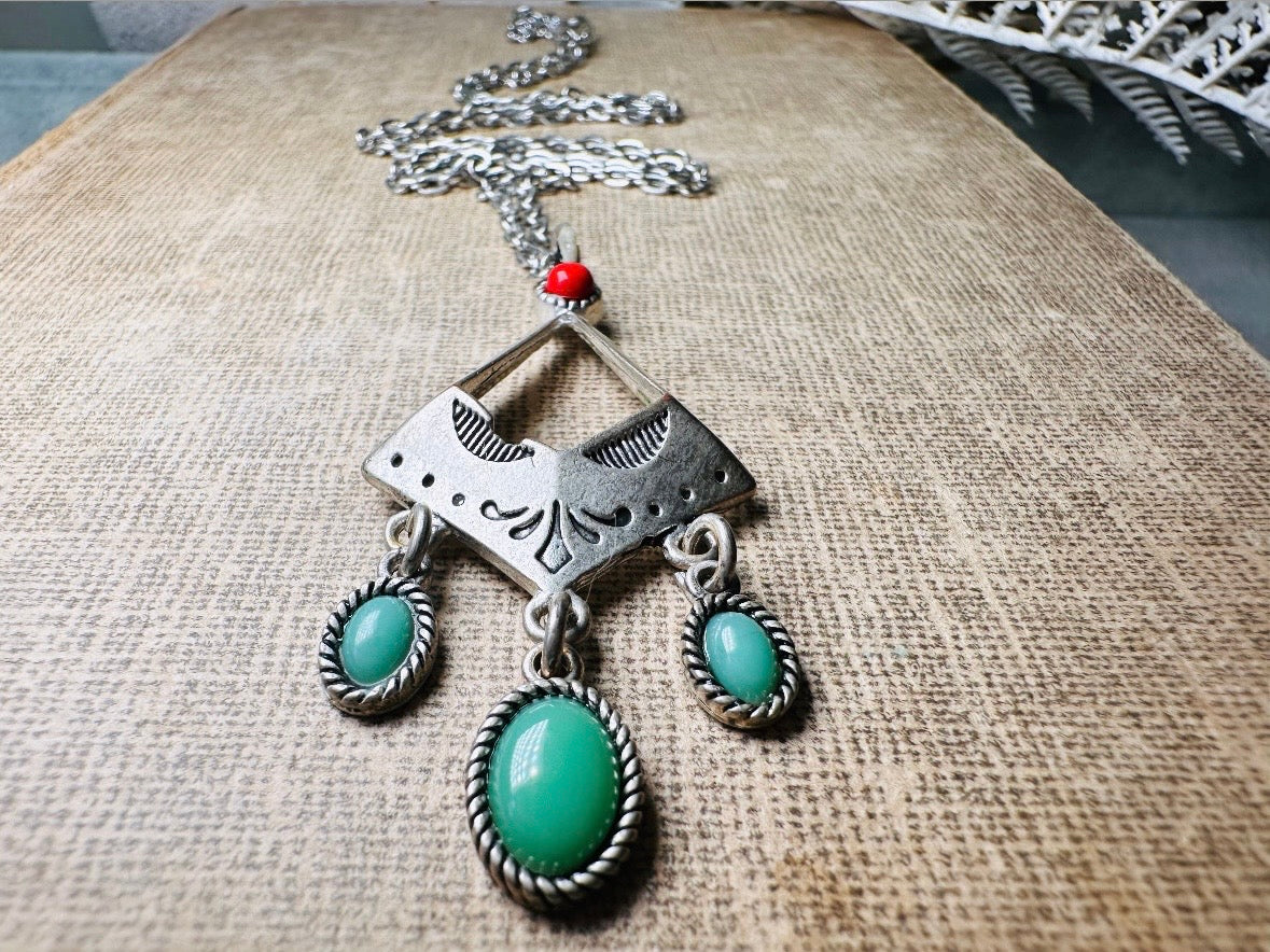 This vintage silver pendant charm necklace is full of bohemian details. Long silver curb chain with a sculptural pendant that has geometric engravings and three turquoise cabochon drops dangling from the focal. There is a red stone set at the top of the pendant. This southwestern style silver vintage necklace would look amazing featured in a necklace stack and beautiful alone.