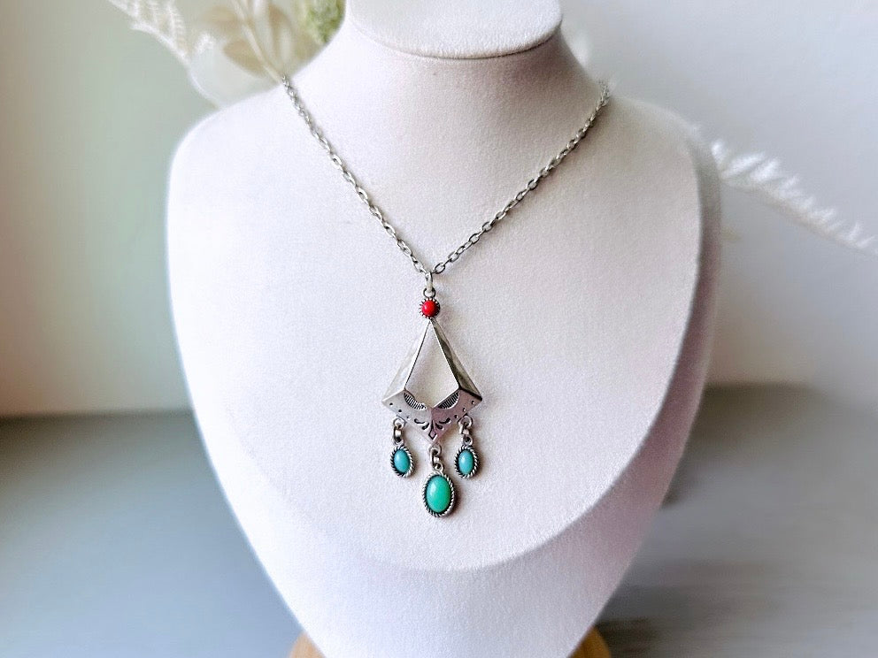 This vintage silver pendant charm necklace is full of bohemian details. Long silver curb chain with a sculptural pendant that has geometric engravings and three turquoise cabochon drops dangling from the focal. There is a red stone set at the top of the pendant. This southwestern style silver vintage necklace would look amazing featured in a necklace stack and beautiful alone.