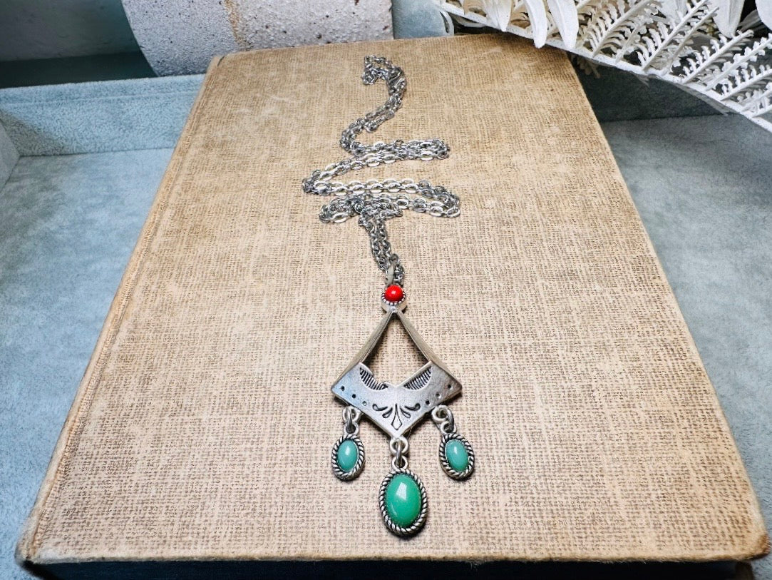 This vintage silver pendant charm necklace is full of bohemian details. Long silver curb chain with a sculptural pendant that has geometric engravings and three turquoise cabochon drops dangling from the focal. There is a red stone set at the top of the pendant. This southwestern style silver vintage necklace would look amazing featured in a necklace stack and beautiful alone.