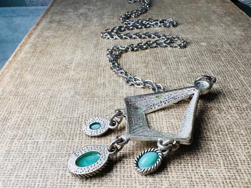 This vintage silver pendant charm necklace is full of bohemian details. Long silver curb chain with a sculptural pendant that has geometric engravings and three turquoise cabochon drops dangling from the focal. There is a red stone set at the top of the pendant. This southwestern style silver vintage necklace would look amazing featured in a necklace stack and beautiful alone.