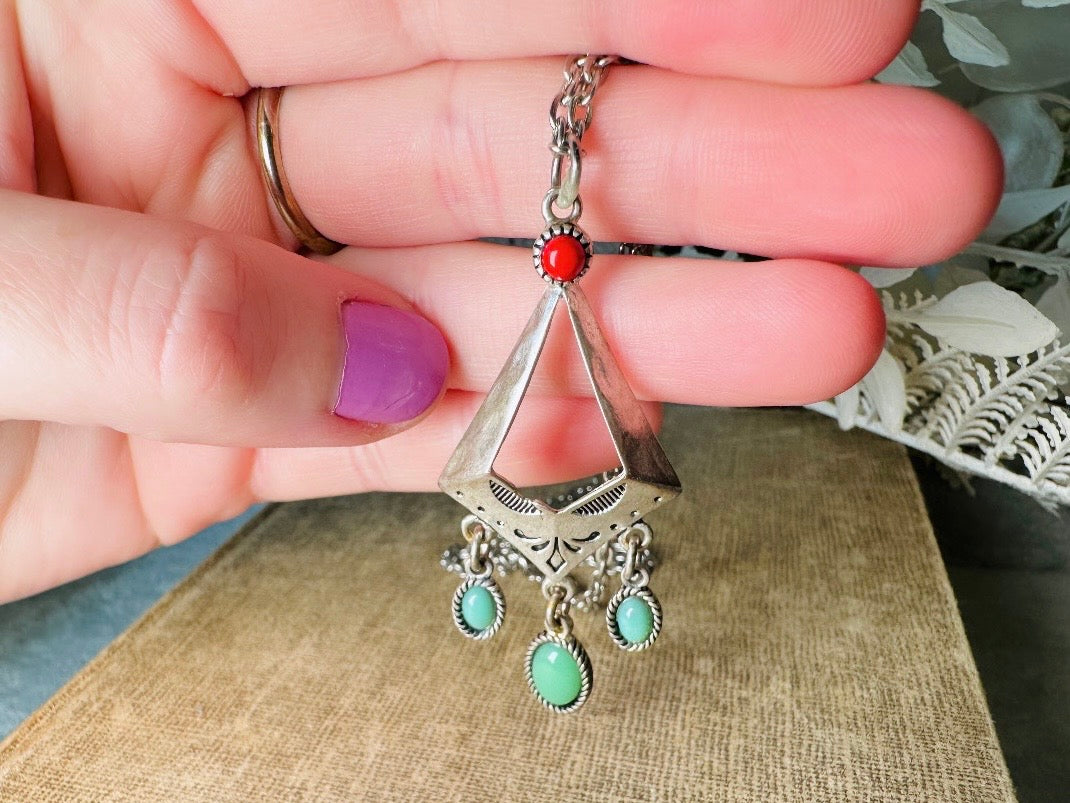 This vintage silver pendant charm necklace is full of bohemian details. Long silver curb chain with a sculptural pendant that has geometric engravings and three turquoise cabochon drops dangling from the focal. There is a red stone set at the top of the pendant. This southwestern style silver vintage necklace would look amazing featured in a necklace stack and beautiful alone.