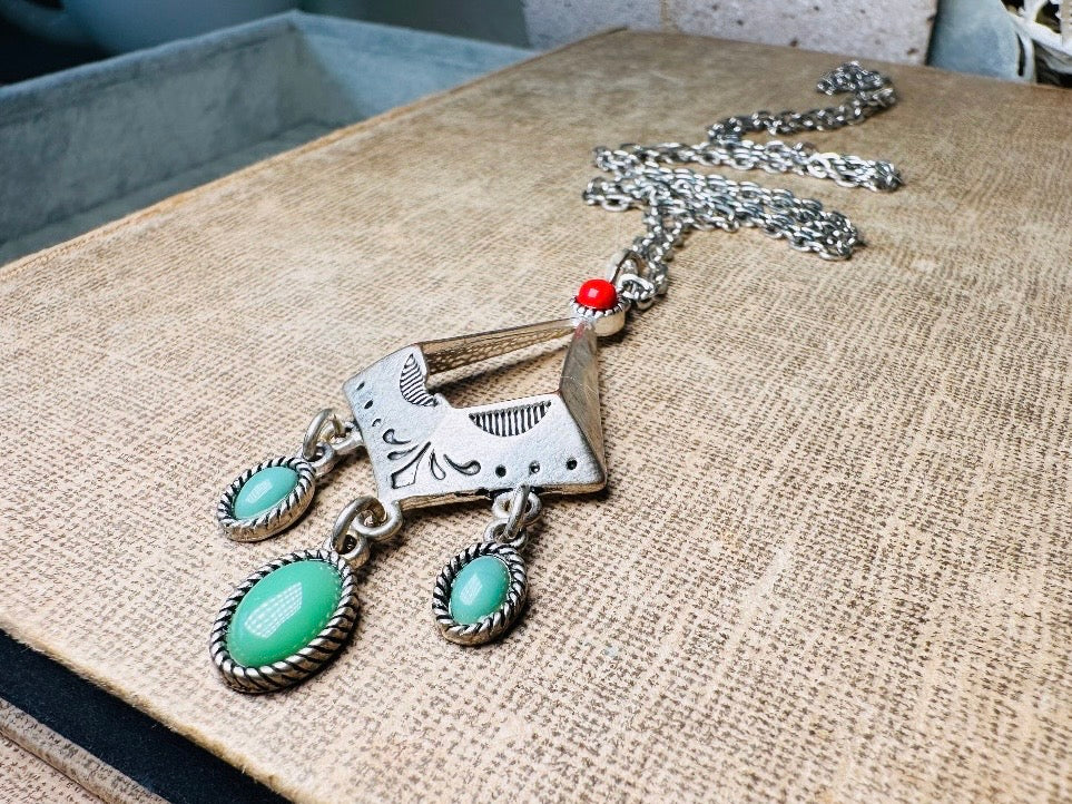 This vintage silver pendant charm necklace is full of bohemian details. Long silver curb chain with a sculptural pendant that has geometric engravings and three turquoise cabochon drops dangling from the focal. There is a red stone set at the top of the pendant. This southwestern style silver vintage necklace would look amazing featured in a necklace stack and beautiful alone.