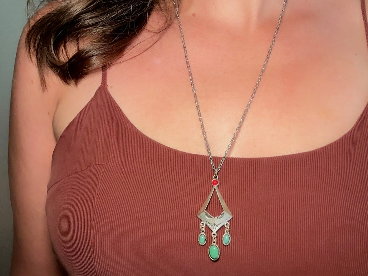 This vintage silver pendant charm necklace is full of bohemian details. Long silver curb chain with a sculptural pendant that has geometric engravings and three turquoise cabochon drops dangling from the focal. There is a red stone set at the top of the pendant. This southwestern style silver vintage necklace would look amazing featured in a necklace stack and beautiful alone.