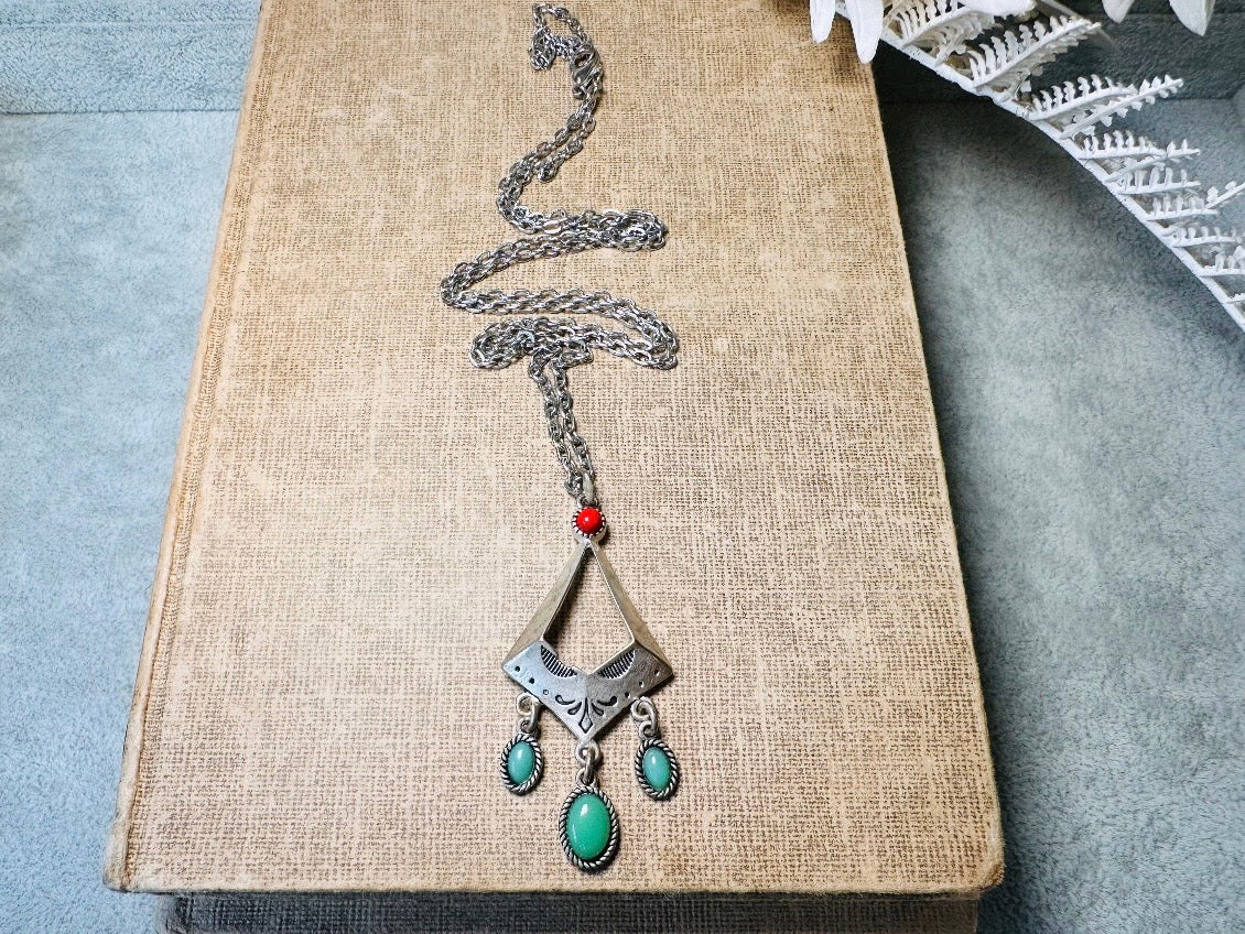 This vintage silver pendant charm necklace is full of bohemian details. Long silver curb chain with a sculptural pendant that has geometric engravings and three turquoise cabochon drops dangling from the focal. There is a red stone set at the top of the pendant. This southwestern style silver vintage necklace would look amazing featured in a necklace stack and beautiful alone.