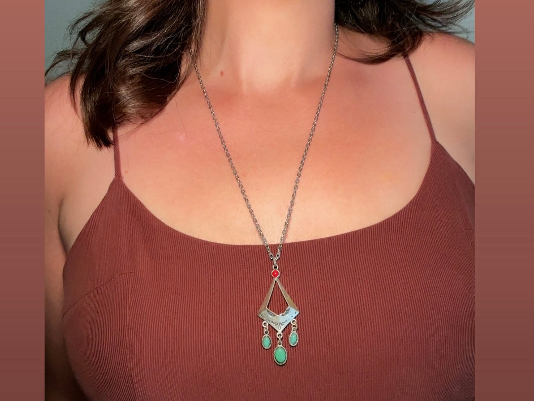 This vintage silver pendant charm necklace is full of bohemian details. Long silver curb chain with a sculptural pendant that has geometric engravings and three turquoise cabochon drops dangling from the focal. There is a red stone set at the top of the pendant. This southwestern style silver vintage necklace would look amazing featured in a necklace stack and beautiful alone.