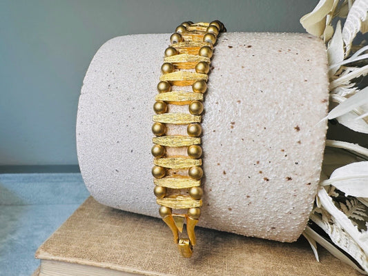 This bold 1970s vintage gold bracelet is so unique- featuring brushed gold bars and smooth polished gold beads. This chunky gold bracelet is timeless and would pair well with a variety of other pieces. &nbsp;An unsigned one of a kind bracelet and perfect jewelry gift for the vintage lover. Structural geometric pieces are currently trending. &nbsp;In great vintage condition, some very minor gold wear on hinge clip- please view all pics.