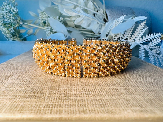 This vintage articulated chunky gold panel bracelet is a showstopper. This signed SC bracelet features articulated gold plated panels with a raised stipple texture throughout. Incredibly well made an in excellent vintage condition. Fastens with a fold over hinge clasp and looks incredible on its own or paired with others for a sensational stack. No flaws to note, please see all pics, from 1973.

Dimensions: 7.75" long, 0.75" wide. Fold over clasp closure.