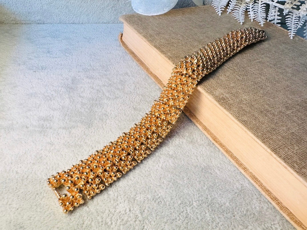This vintage articulated chunky gold panel bracelet is a showstopper. This signed SC bracelet features articulated gold plated panels with a raised stipple texture throughout. Incredibly well made an in excellent vintage condition. Fastens with a fold over hinge clasp and looks incredible on its own or paired with others for a sensational stack. No flaws to note, please see all pics, from 1973.

Dimensions: 7.75" long, 0.75" wide. Fold over clasp closure.
