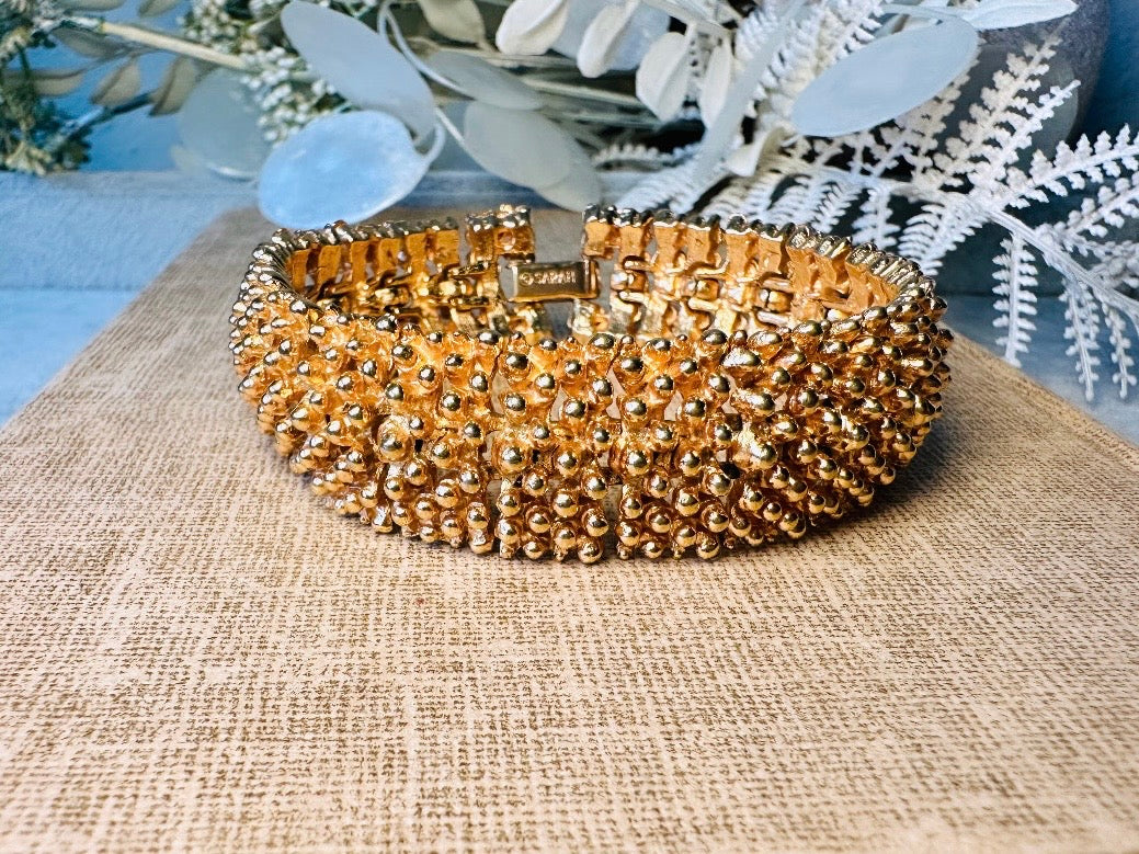 This vintage articulated chunky gold panel bracelet is a showstopper. This signed SC bracelet features articulated gold plated panels with a raised stipple texture throughout. Incredibly well made an in excellent vintage condition. Fastens with a fold over hinge clasp and looks incredible on its own or paired with others for a sensational stack. No flaws to note, please see all pics, from 1973.

Dimensions: 7.75" long, 0.75" wide. Fold over clasp closure.
