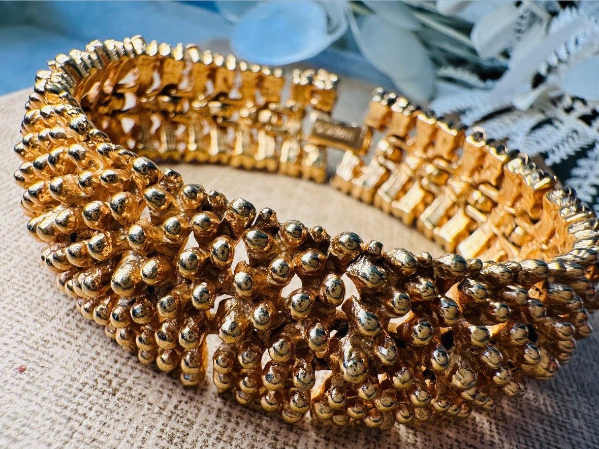 This vintage articulated chunky gold panel bracelet is a showstopper. This signed SC bracelet features articulated gold plated panels with a raised stipple texture throughout. Incredibly well made an in excellent vintage condition. Fastens with a fold over hinge clasp and looks incredible on its own or paired with others for a sensational stack. No flaws to note, please see all pics, from 1973.

Dimensions: 7.75" long, 0.75" wide. Fold over clasp closure.
