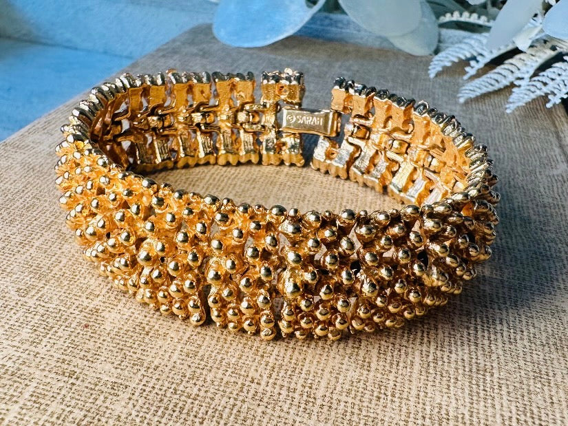 This vintage articulated chunky gold panel bracelet is a showstopper. This signed SC bracelet features articulated gold plated panels with a raised stipple texture throughout. Incredibly well made an in excellent vintage condition. Fastens with a fold over hinge clasp and looks incredible on its own or paired with others for a sensational stack. No flaws to note, please see all pics, from 1973.

Dimensions: 7.75" long, 0.75" wide. Fold over clasp closure.
