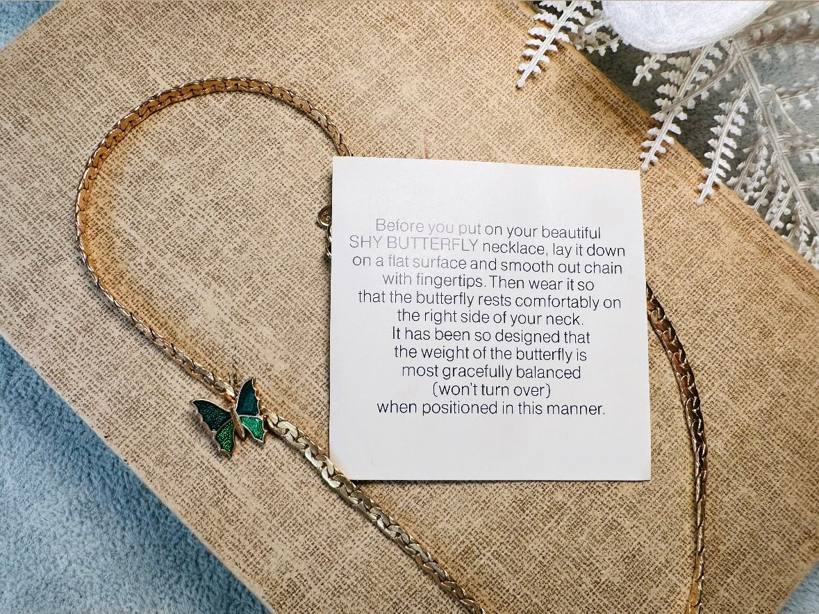 This vintage green and gold shy butterfly necklace is an absolute beauty from the 1970s. Elegantly designed to be worn with the butterfly charm on the right side, this dainty choker necklace is so lovely. The chain is a delicate classic gold herringbone chain, the butterfly is two toned in deep green and teal enamel with a pearlized shimmer. Arrives wrapped beautifully and ready to gift to the butterfly lover in your life. &nbsp;An excellent gift or a thoughtful keepsake for a friend. 