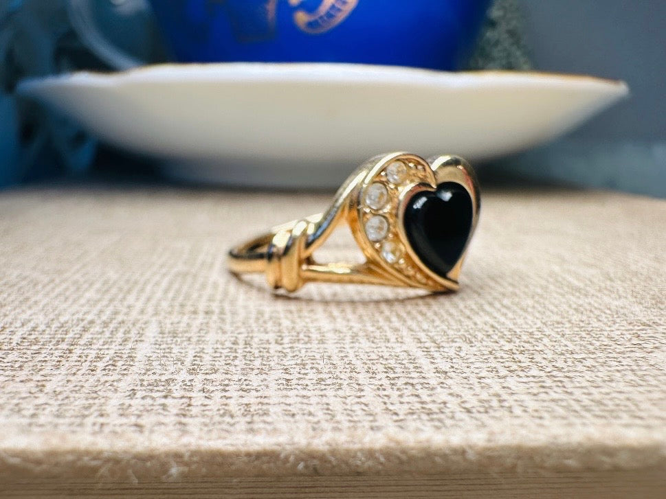 Gold ring with a black heart stone on a textured surface