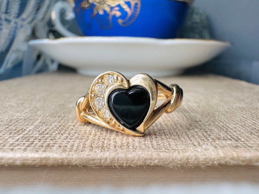 Gold ring with black heart stone on a textured surface