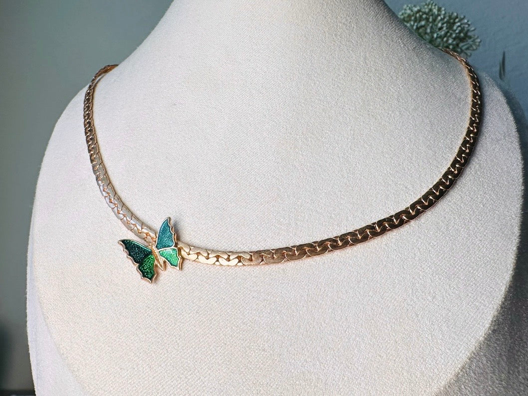 This vintage green and gold shy butterfly necklace is an absolute beauty from the 1970s. Elegantly designed to be worn with the butterfly charm on the right side, this dainty choker necklace is so lovely. The chain is a delicate classic gold herringbone chain, the butterfly is two toned in deep green and teal enamel with a pearlized shimmer. Arrives wrapped beautifully and ready to gift to the butterfly lover in your life. &nbsp;An excellent gift or a thoughtful keepsake for a friend. 