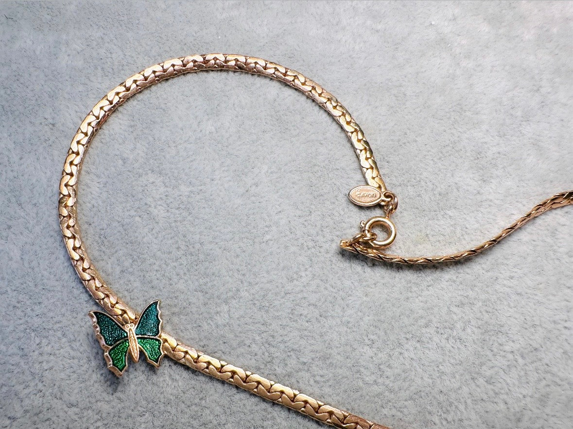 This vintage green and gold shy butterfly necklace is an absolute beauty from the 1970s. Elegantly designed to be worn with the butterfly charm on the right side, this dainty choker necklace is so lovely. The chain is a delicate classic gold herringbone chain, the butterfly is two toned in deep green and teal enamel with a pearlized shimmer. Arrives wrapped beautifully and ready to gift to the butterfly lover in your life. &nbsp;An excellent gift or a thoughtful keepsake for a friend. 
