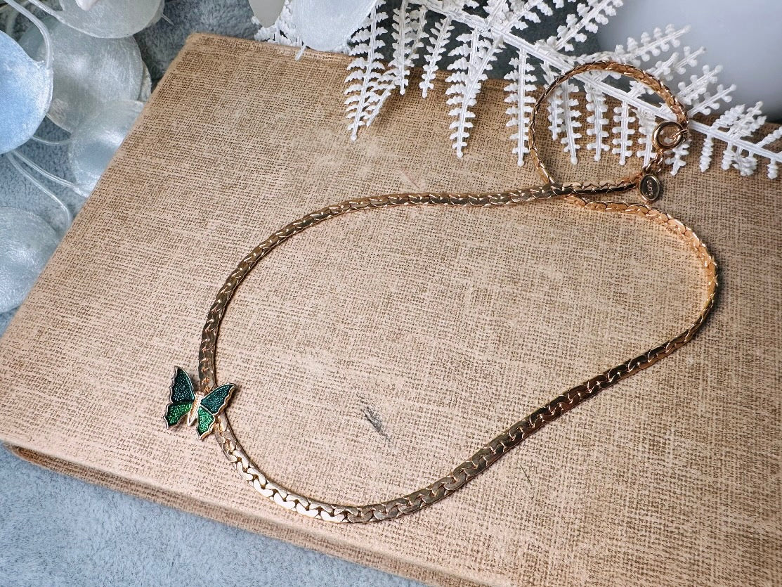 This vintage green and gold shy butterfly necklace is an absolute beauty from the 1970s. Elegantly designed to be worn with the butterfly charm on the right side, this dainty choker necklace is so lovely. The chain is a delicate classic gold herringbone chain, the butterfly is two toned in deep green and teal enamel with a pearlized shimmer. Arrives wrapped beautifully and ready to gift to the butterfly lover in your life. &nbsp;An excellent gift or a thoughtful keepsake for a friend. 